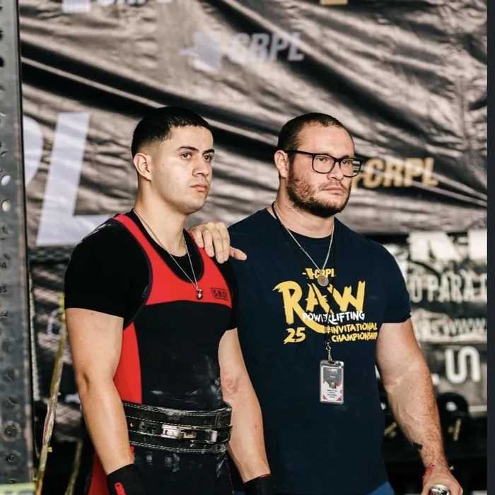 Douglas Lutz standing with an athlete in front of the CRPL backdrop